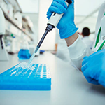 A researcher holding a pipette over a specimen tray.