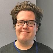 Profile picture of Eric Bock with curly hair and eyeglasses, smiling.