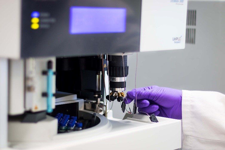 A researcher’s gloved hand checking a lab machine.