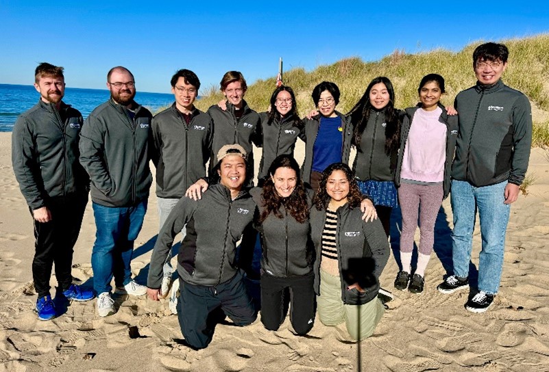 Dr. Dickinson with 11 others standing and kneeling on the beach for a photo.
