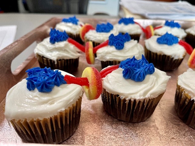 Cupcakes on a serving tray. Pairs of cupcakes are connected by a candy string that's going through a gummy peach ring to resemble two daughter cells and a midbody.