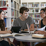 A group of students sitting around laptops and talking.